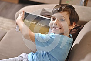 Online training education and communiction. Quarantine. Happy smiling kid boy holds incoming call tablet