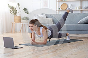 Sporty Girl Exercising at Home, using laptop