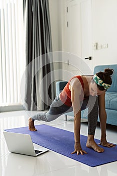 Online training. Woman doing yoga exercises and watching tutorial lesson on laptop