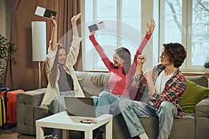 Online travel booking platform advertisement. Happy young friends planning trip, sitting at home and using laptop for