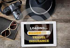 Online travel insurance loading on computer digital tablet with hipster accessories