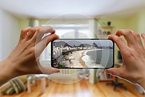 Online travel to Copacabana Beach in Rio De Janeiro, Brazil. Using a smartphone at home