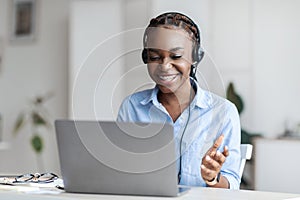 Online Tutoring. Black Female Tutor In Headset Having Video Conference With Laptop photo