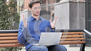 Online Video Chat on Laptop by Young Man Sitting on Bench