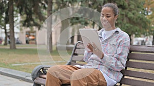 Online Video Chat on Tablet by African Woman Sitting Outdoor on Bench