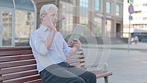 Online Video Chat on Tablet by Old Man Sitting Outdoor on Bench