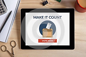 Online voting concept on tablet screen with office objects on wooden desk
