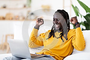 Online Win. Overjoyed Young Black Man Celebrating Success With Laptop At Home