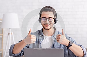 Online work. Smiling guy with headset shows sign excellent with hand