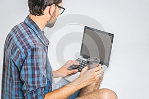 Online working concept. Casual business man relaxed working and browsing internet on laptop computer with coffee. Freelance