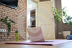 Online workout at home concept. Laptop computer on yoga mat on floor.