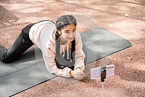 Online workout in modern outdoors sportground performed by young Indian woman