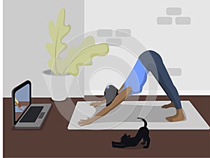 Online yoga lesson. Girl and cat do online yoga on the mat at home during quarantine during the coronavirus pandemic