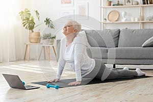 Online Yoga. Senior Woman Standing In Cobra Pose In Front Of Laptop