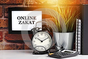 ONLINE ZAKAT text with alarm clock, books and vase on brick background
