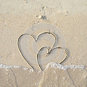 Ð¡onnected hearts drawn on wet sand