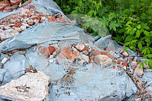 Ð¡onstruction garbage, debris and waste rubble in a remote green area. Nature and soil pollution concept.