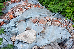 Ð¡onstruction garbage, debris and waste rubble in a remote green area. Nature and soil pollution concept.