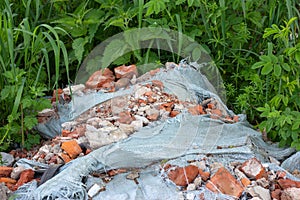 Ð¡onstruction garbage, debris and waste rubble in a remote green area. Nature and soil pollution concept.