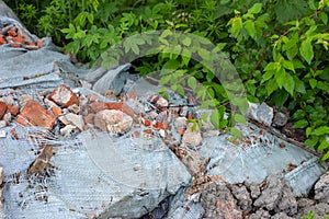 Ð¡onstruction garbage, debris and waste rubble in a remote green area. Nature and soil pollution concept.