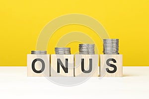 onus text written on wooden block with stacked coins on yellow background photo