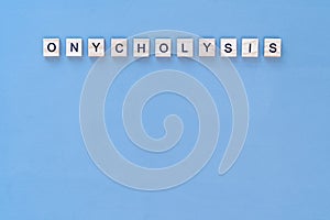 Onycholysis nail. The inscription Onycholysis in wooden letters on a blue background photo