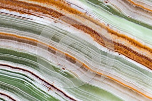 Onyx gemstone texture close up. Green, white, brown and orange stripes. Natural stone mineral background photo