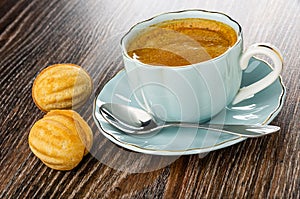 Ð¡ookies in nut shape with filling, cup with black coffee, spoon in saucer on wooden table