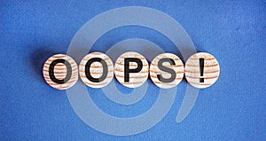 Oops sign on wooden cut circles. Beautiful blue background, copy space. Concept