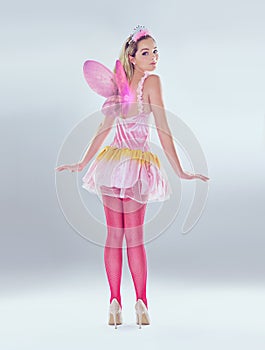 Oops, you caught me. A full length shot of a cute fairy dressed in pink.