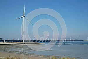 Oosterscheldekering with windmill seen from the shore of Noord Beveland