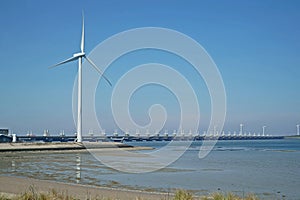 Oosterscheldekering with windmill seen from the shore of Noord Beveland photo