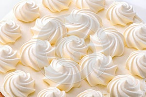 Op of cake decorated with whipped cream curls close-up on white background