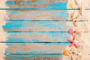 Op view of beach sand with shells, starfish on wood plank in blue sea