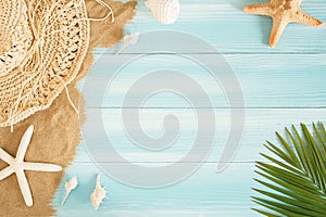 Op view of sea straw hat and sea shells on the sea sand on a blue wooden background, Summer concept on empty. Palm leaf blue wood