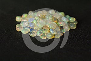 Opals gemstone from Ethiopia lies on black background. White fire opals with rainbowlike fire. Natural fire Ethiopian opal, small
