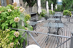 Open-air cafe in the garden with empty iron furniture on wooden terrace