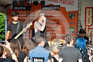 Open air concert of rock music band called The Paranoid. Guitarist and singer stand in front of group of young fans.