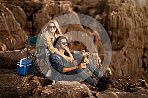 Open-Air Picnic. Happy Young Couple Relaxing In Camping Chairs On Beachrocks