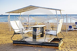 Open alcove, bar, cafe, terrace with table and chairs for visitors on sand beach, tropical sea resort.Summer vacation on warm