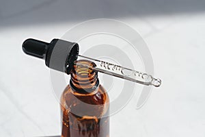 Open amber bottle with dropper pipette with serum or essential oil and shadows. Skincare products, natural cosmetic on