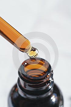 Open amber bottle with dropper pipette with serum or essential oil and shadows. Skincare products, natural cosmetic on