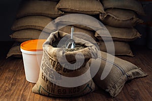 Open bag full of raw coffee beans with metal scoop, in the background of the warehouse