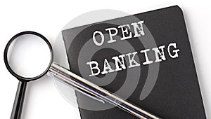 OPEN BANKING - business concept, magnifier with white text message on black notebook