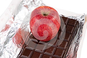 Open bar chocolate in aluminium foil with red single apple