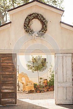 Open barn doors with wreath hanging at the top opening up to a wicker rocking chair