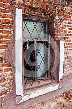 An open barred window on a crumbling brick wall