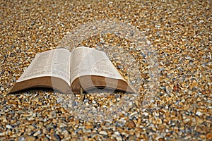 Open bible on beach pebbles
