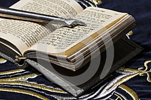Open bible book in Hebrew with silver pointing hand