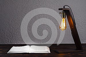 Open Bible book, on a wooden table. Desk lamp. Workplace. Desktop.